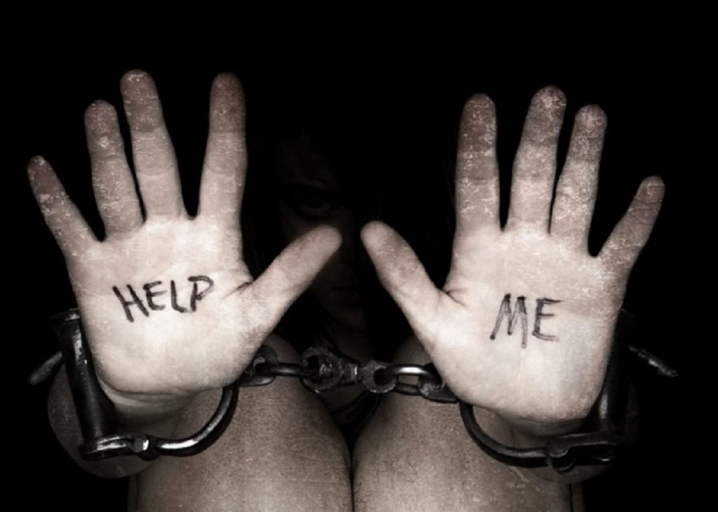 Hands in chains with 'Help Me' written on palms — the reality of human trafficking